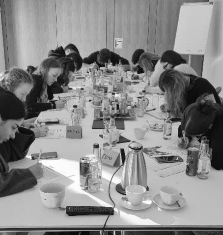12 Azubis sitzen an einem Tisch und arbeiten